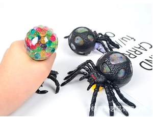 Detail of hand squeezing spider stress ball showing colorful water beads popping out