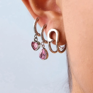Macro view of silver pin earrings and pink heart-shaped crystal charms for women