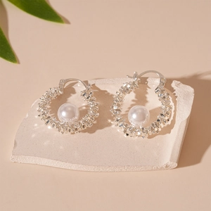 Boucles d'oreilles créoles argentées avec perles sur un support en pierre minimaliste