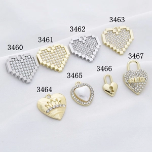 Assorted heart pendants with rhinestones, pearls and crown designs on white fabric