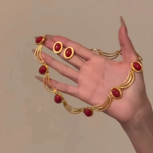 Vintage jewelry set with gold metal necklace and red gemstone earrings on model