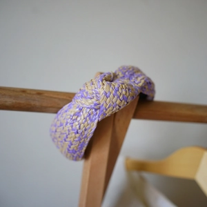Detail of hand-woven purple and beige raffia headband with a twisted knot design