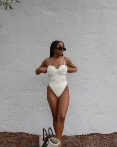 Detailed view of white one-piece swimsuit featuring 3D floral rosettes and high-cut design