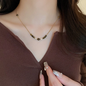 Minimalist gold tiger eye bead necklace with pearls on a brown sweater background