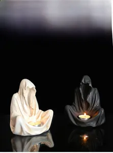 Close-up of ghost wizard resin candle holders with warm tea light glow in a dark setting