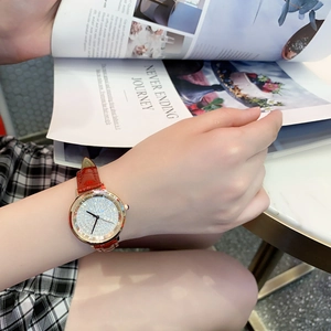Elegant rose gold watch with red leather strap and diamond dial worn by a model