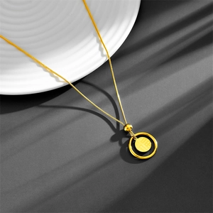 Détail d'un collier doré double couche avec pendentif anneau noir et or gravé du symbole 'Fu'