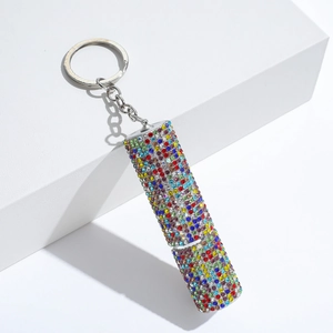 Macro detail of silver keychain with a cylindrical charm covered in colorful rhinestones
