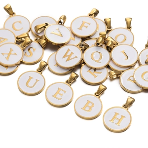 Detailed macro view of gold-plated stainless steel letter pendants with white enamel finish