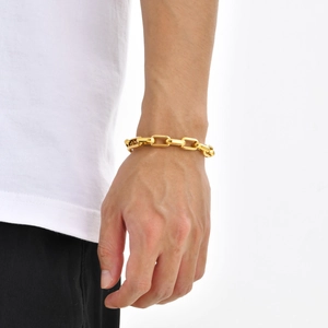 Detailed close-up of a gold-plated rectangular link bracelet worn on a female wrist