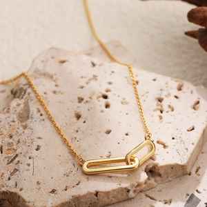 Close-up of gold interlocking rectangular rings on a stone base for minimalist necklace