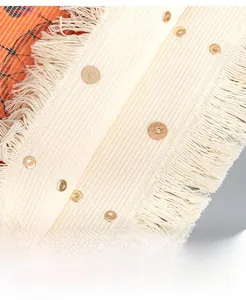 Macro detail of canvas tote bag showing fringe trim and golden magnetic snap closures