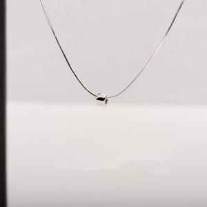 Detailed view of a polished silver cube pendant on a sleek titanium steel chain
