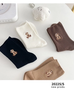 Détails de quatre chaussettes en coton côtelé aux tons terre avec broderie ours et 24