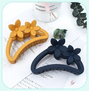 Close-up of matte resin flower hair claws in amber yellow and navy blue colors