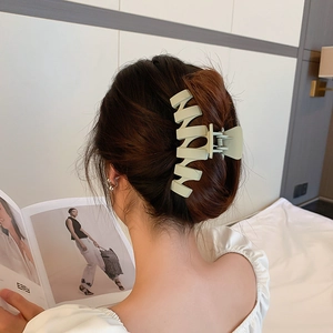 Modèle portant une grande pince à cheveux vert clair mat avec design géométrique ondulé