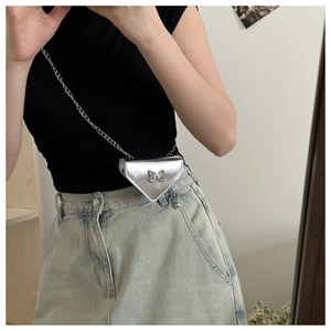Close-up of silver triangular mini bag with metal butterfly detail and chain strap