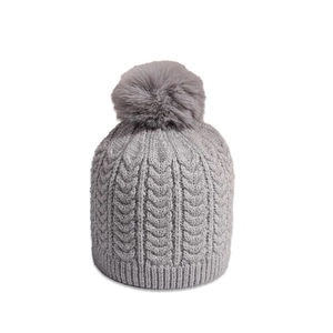 Detailed view of grey cable knit winter hat featuring a fluffy faux fur pompom top