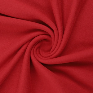 Macro detail of red knitted fabric texture showing soft spiral drapes and material quality