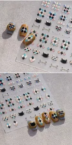 Detailed view of plaid and heart nail stickers with gold accents and cat motifs