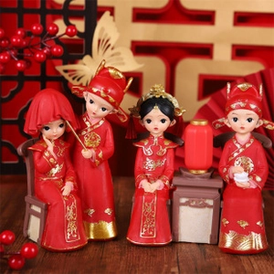 Detailed close-up of four miniature Chinese wedding figurines in red and gold attire