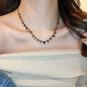 Détail du collier en œil de tigre avec perles brunes irrégulières et billes métalliques