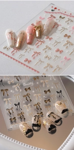 Macro shot of 3D gold-stamped bow nail stickers in black and pink with mirror reflections