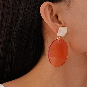 Minimalist resin geometric earrings with orange round pendant shown on a female model