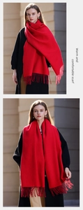 Detailed view of red winter scarf with soft fringes worn by a model in warm light