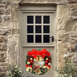 Christmas wreath with red bow, gold bells and Merry Christmas sign on a wooden door