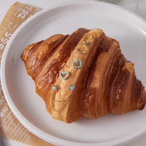 Detailaufnahme der 18K vergoldeten Ohrringe mit Türkissteinen auf einem Croissant
