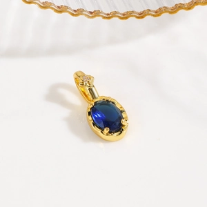 Detailed macro of a 18k gold plated turtle pendant with oval deep blue cubic zirconia