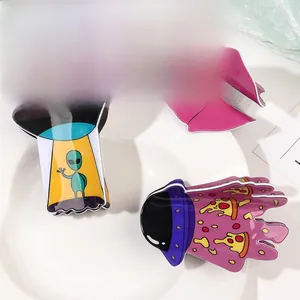 Detailed view of three acrylic hair claws featuring UFO, alien, and pizza patterns