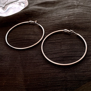 Macro shot of rose gold large hoop earrings with polished metal texture and clasp detail
