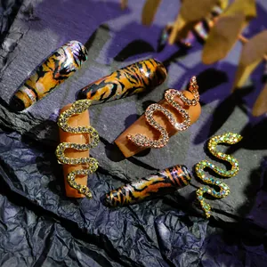 Macro detail of snake-shaped nail art charms with sparkling zircons on rock texture