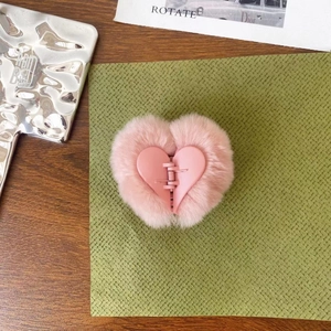 Detail of pink faux fur heart hair claw clip with matte finish center on green paper