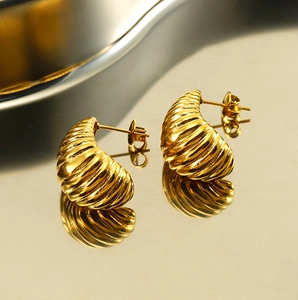 Macro shot of gold twisted croissant stud earrings featuring elegant spiral texture details