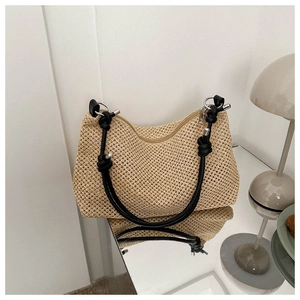 Detail of hand-woven beige straw tote bag featuring contrast black knotted leather straps