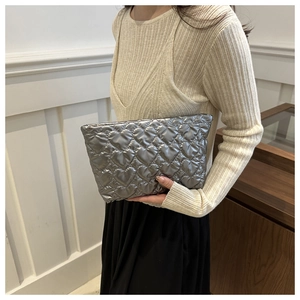 Silver heart quilted pouch held by model showing compact size and metallic texture