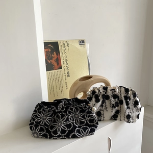Detail of floral embroidery and pearl zipper charms on black and white fabric clutch bags