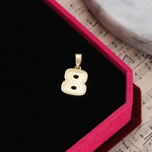 Macro shot of gold number 8 pendant with round texture on black velvet jewelry box