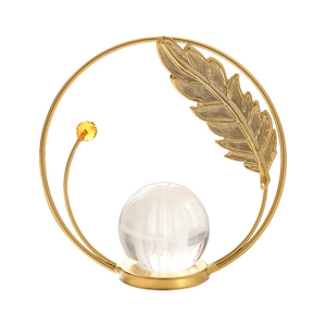 Modern gold metal ring ornament with feather detail and crystal ball on white background