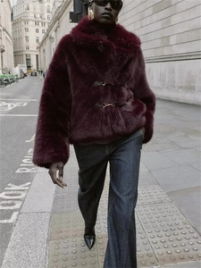Detail of burgundy faux fur jacket featuring plush texture and ornate metal buckle closure