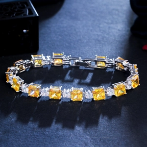 Macro shot of princess cut yellow zircons and white round diamonds on a silver-plated bracelet