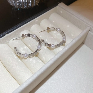 Detailed close-up of silver pearl earrings displayed in an elegant jewelry gift box