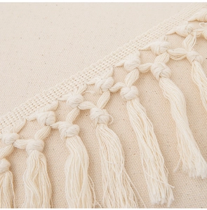 Close-up of tassels and textures on a beige cotton linen bohemian cushion cover