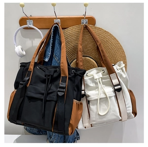 Detail of color-block canvas tote bag with drawstring closure and side pocket features