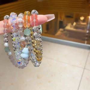 Detail showing various crystal beads bracelets with a white gourd charm and metal accents