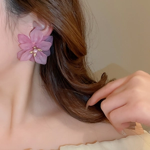 Detail of pink resin flower petals earring with golden stamen on female model