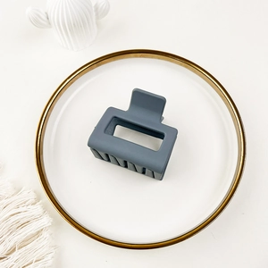 Detailed view of matte grayish-blue square hair claw clip on a decorative white plate